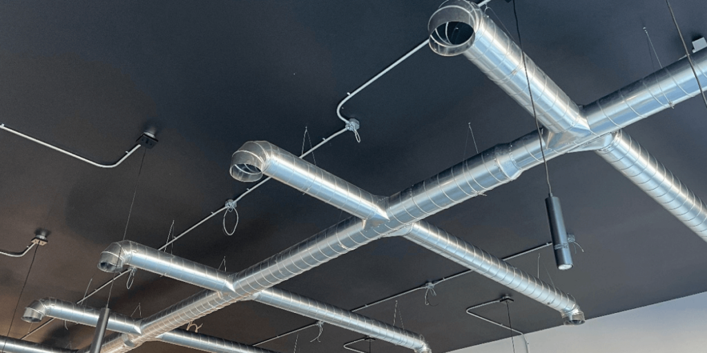 a group of silver pipes on a black ceiling